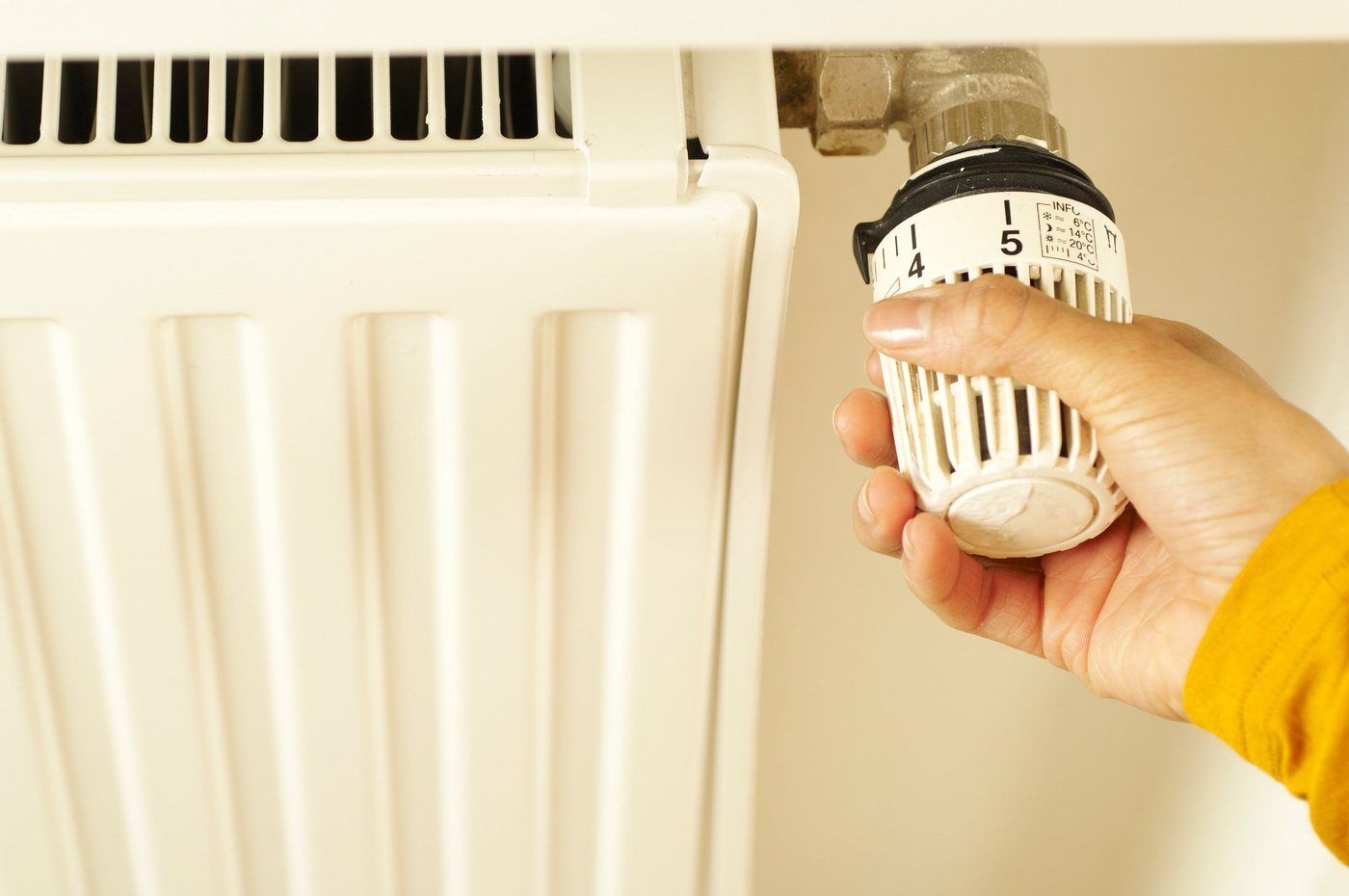 A hand adjusting a thermostatic radiator valve