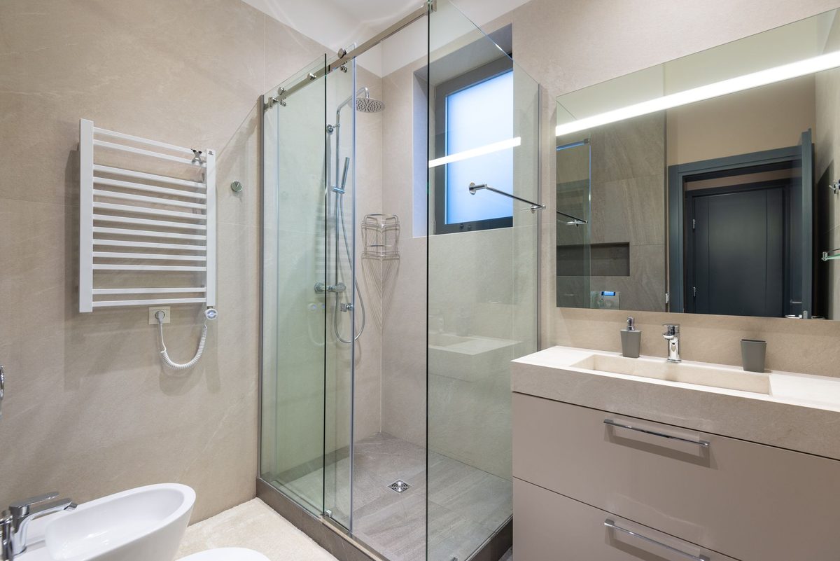 A walk-in shower enclosure with a heated towel rail and large-format wall tiling — the kind of full bathroom fit handled here as one job, tiling included.