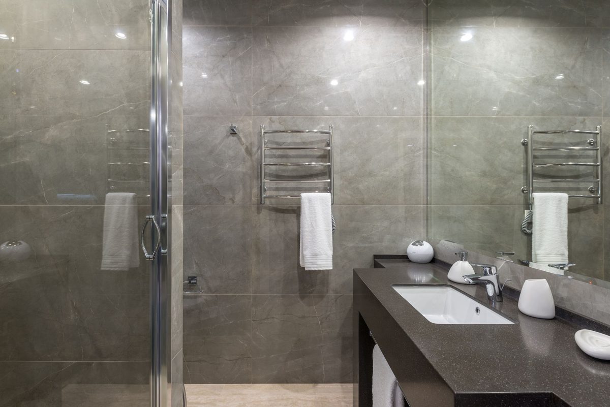 Large-format tiling run floor to ceiling in a shower room — flat background, planned set-out, straight grout lines.