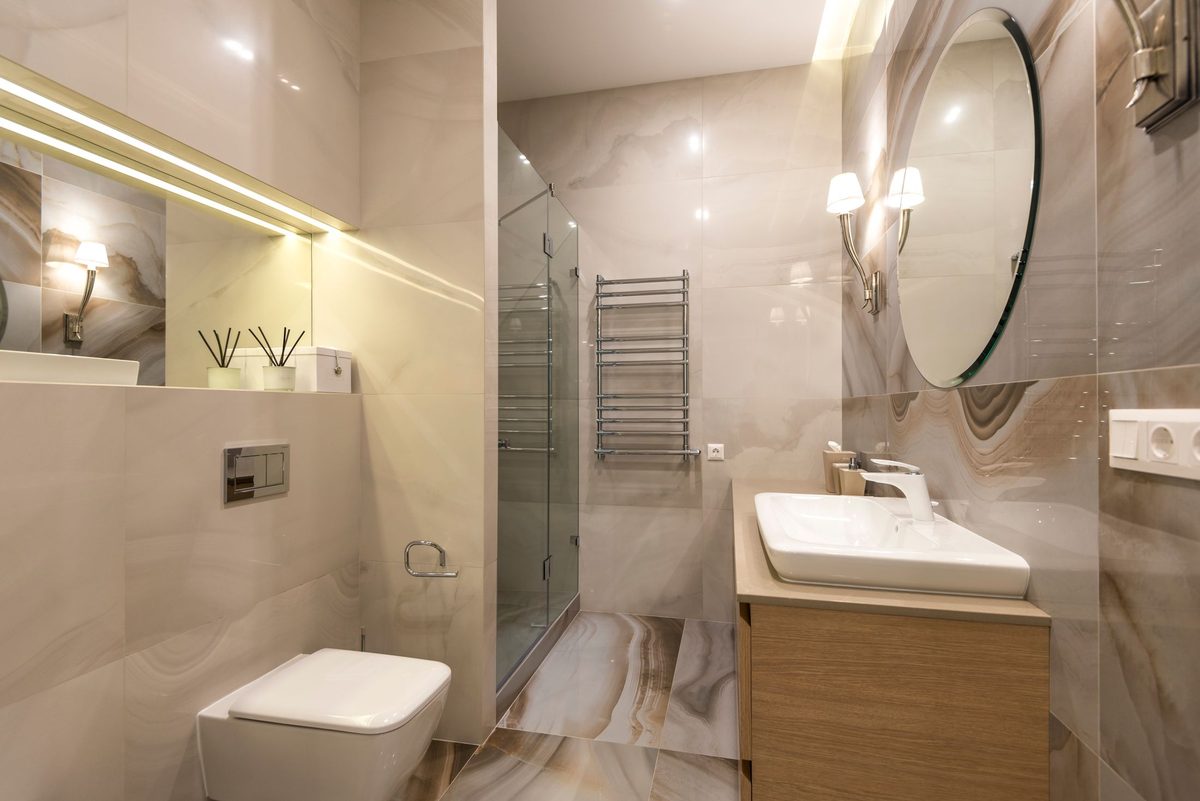 A glazed shower enclosure and vanity unit in a light, neutral bathroom — first fix, fitting and final connections all under one pair of hands.