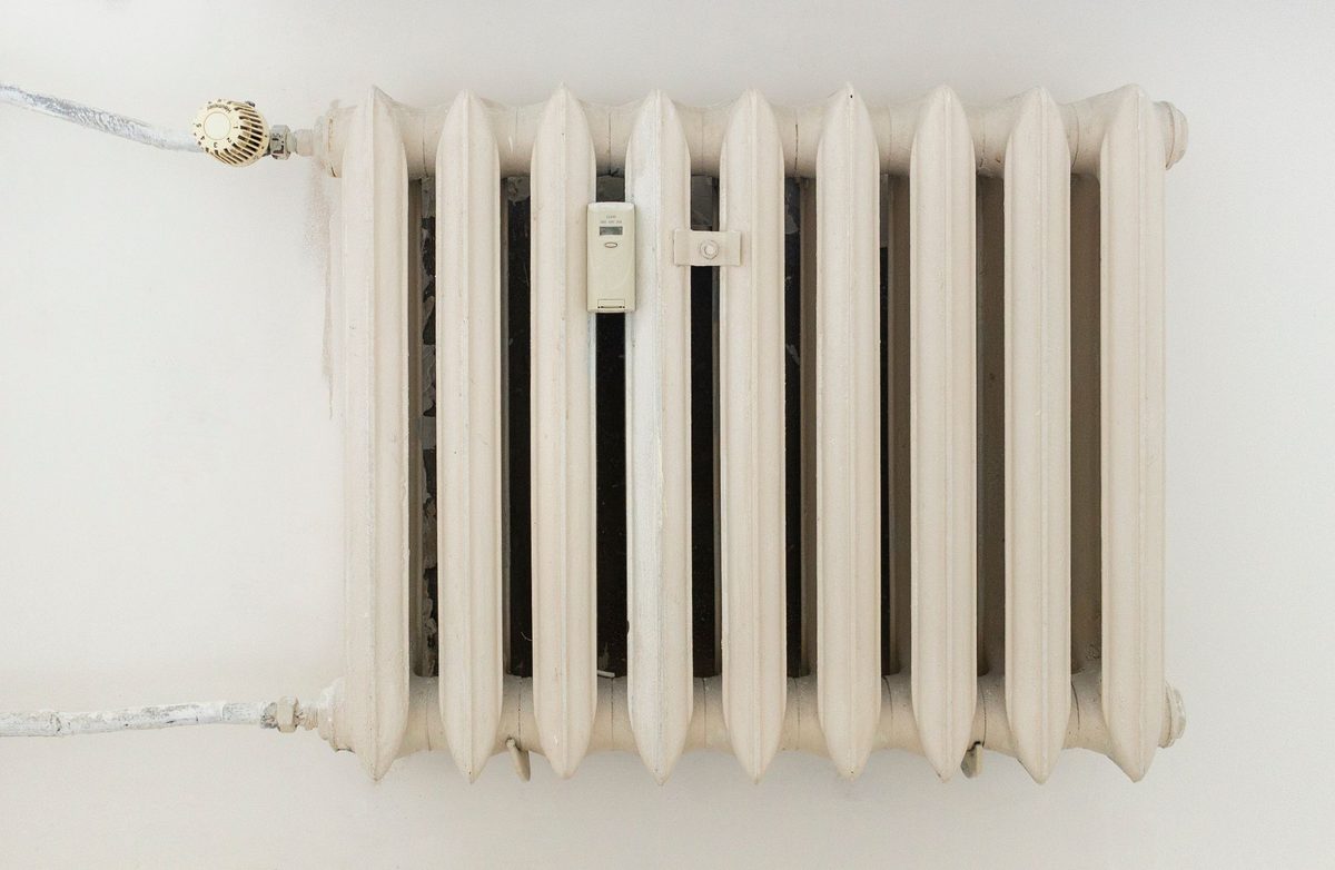 A traditional column radiator on a plain wall — radiators fitted, moved and replaced as part of heating installation and repair work.