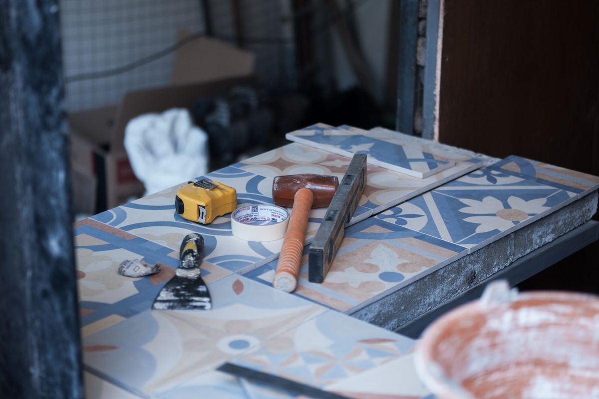 Patterned floor tiles being set out and bedded — preparation and layout are where a tiled floor is won or lost.